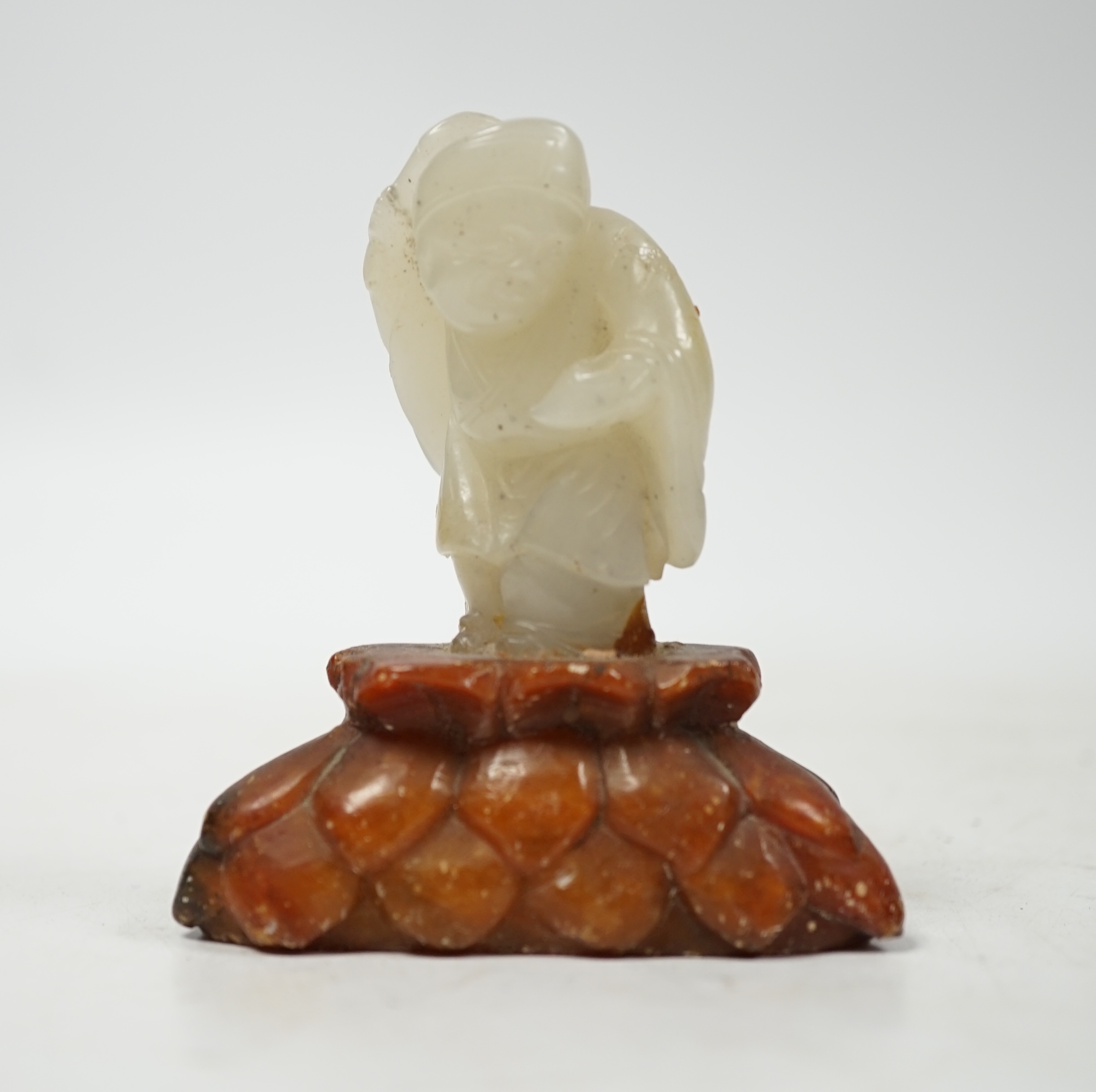 A Chinese pale celadon jade figure of a man holding a fly whisk, Qing dynasty, 5.2cm high, soapstone stand, total height 8cm high